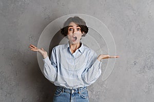 Young brunette woman expressing surprise while holding copyspace