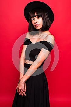 Young brunette woman in fluppy hat and black clothes on red background
