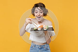 Young brunette woman girl in casual clothes hold in hand makizushi sushi roll served on black plate traditional japanese