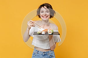 Young brunette woman girl in casual clothes hold in hand makizushi sushi roll served on black plate traditional japanese