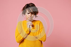 Young brunette woman girl in yellow sweater posing isolated on pastel pink background, studio portrait. People sincere