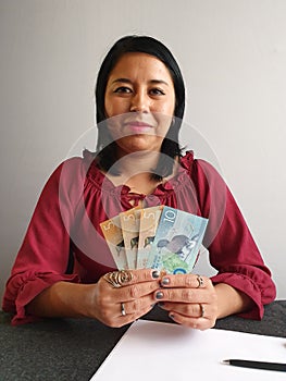 young brunette woman grabbing and showing New Zealand money