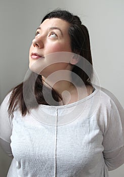 Young brunette woman with green eyes and natural beauty portrait looking up to a high window