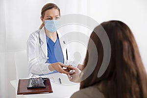 Young brunette woman having consultation at doctor office during coronavirus and flu outbreak. Female doctor wearing