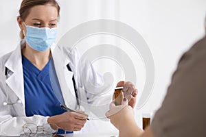 Young brunette woman having consultation at doctor office during coronavirus and flu outbreak. Female doctor wearing