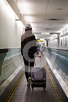 Young brunette woman with her luggage in an airport concourse.