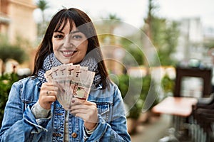 Young brunette woman holding arabia saudi riyal banknotes at the city photo