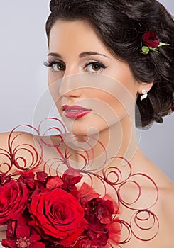 A young brunette woman holding red feathers