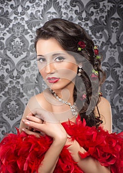 A young brunette woman holding red feathers