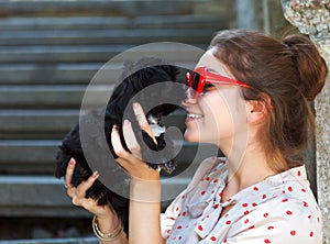 Young brunette woman hugging her lap dog puppy