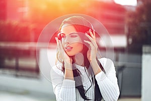 Young brunette woman listening to music by headphones outdoor