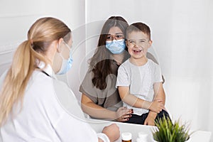 Young brunette woman with little boy having consultation at pediatrician office. Doctor, child and mother wearing