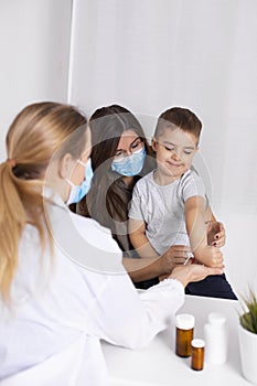 Young brunette woman with little boy having consultation at pediatrician office. Doctor, child and mother wearing