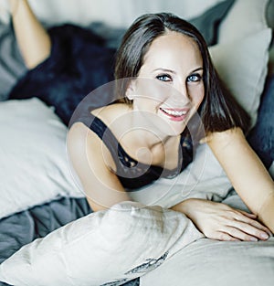 Young brunette woman in loft laying on bed smiling