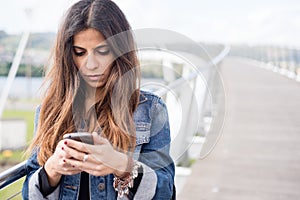 Young brunette woman looking her smart phone