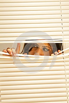 Young Brunette Woman Looking Through Window Blinds photo