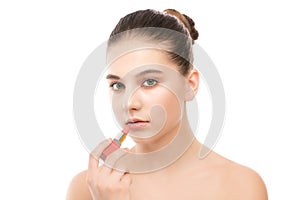 Young brunette woman with perfect clean face applying lipstick. Isolated on a white.