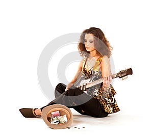A young brunette woman playing on the guitar