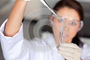 Young brunette woman pouring a liquid in a tube