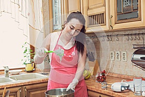 A young brunette woman prepares pastries in her kitchen