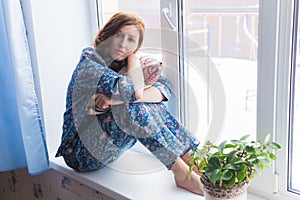 Young red-haired woman relaxing at home. Quarantine, isolation, coronavirus pandemic world. Stay at home.