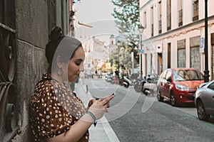 Young brunette woman searching something in her phone in the street sidewalk