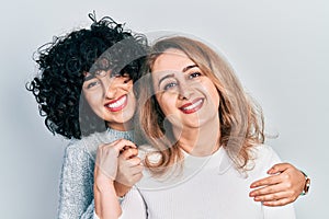 Young brunette woman and senior woman standing over isolated background