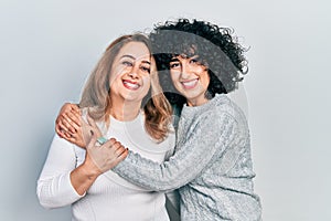 Young brunette woman and senior woman standing over isolated background