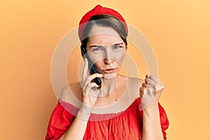 Young brunette woman with short hair having conversation talking on the smartphone annoyed and frustrated shouting with anger,