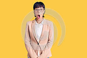 Young brunette woman with short hair wearing business jacket and glasses afraid and shocked with surprise expression, fear and