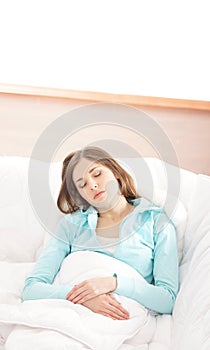 A young brunette woman sleeping on a white bed