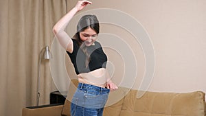 Young brunette woman smiling wearing loose jeans after losing weight
