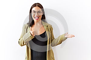 Young brunette woman standing over isolated background showing palm hand and doing ok gesture with thumbs up, smiling happy and