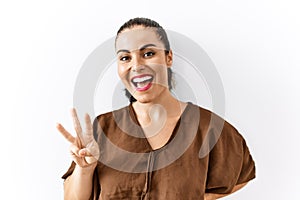 Young brunette woman standing over isolated background showing and pointing up with fingers number three while smiling confident