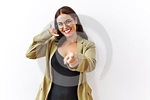 Young brunette woman standing over isolated background smiling doing talking on the telephone gesture and pointing to you