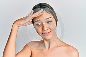 Young brunette woman standing topless showing skin stressed and frustrated with hand on head, surprised and angry face