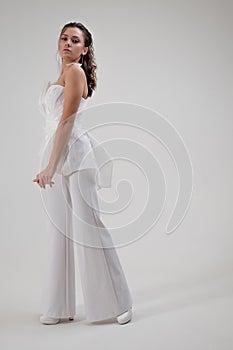 A young brunette woman in a stylish and elegant pantsuit. Wedding suit with trousers, modern style.