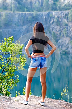 young brunette woman walking on the shore of a mountain lak