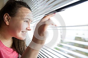 Young brunette woman watching out from the window, stalking, observation concept