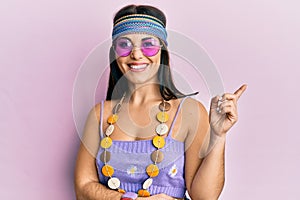 Young brunette woman wearing bohemian and hippie style smiling happy pointing with hand and finger to the side