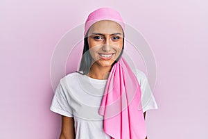 Young brunette woman wearing breast cancer support pink scarf looking positive and happy standing and smiling with a confident