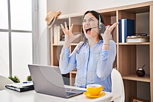 Young brunette woman wearing call center agent headset crazy and mad shouting and yelling with aggressive expression and arms