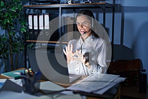 Young brunette woman wearing call center agent headset working late at night disgusted expression, displeased and fearful doing