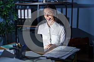 Young brunette woman wearing call center agent headset working late at night with a happy and cool smile on face