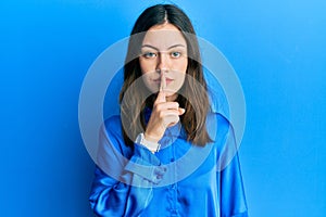 Young brunette woman wearing casual blue shirt asking to be quiet with finger on lips