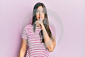 Young brunette woman wearing casual clothes over pink background asking to be quiet with finger on lips