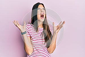 Young brunette woman wearing casual clothes over pink background crazy and mad shouting and yelling with aggressive expression and