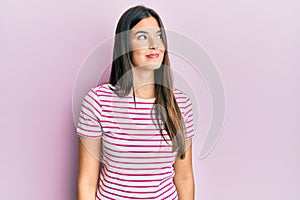 Young brunette woman wearing casual clothes over pink background smiling looking to the side and staring away thinking