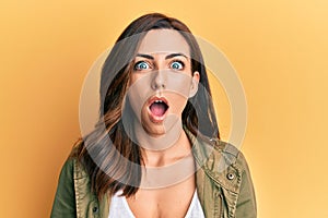 Young brunette woman wearing casual clothes over yellow background afraid and shocked with surprise and amazed expression, fear