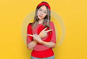 Young brunette woman wearing casual clothes pointing to both sides with fingers, different direction disagree